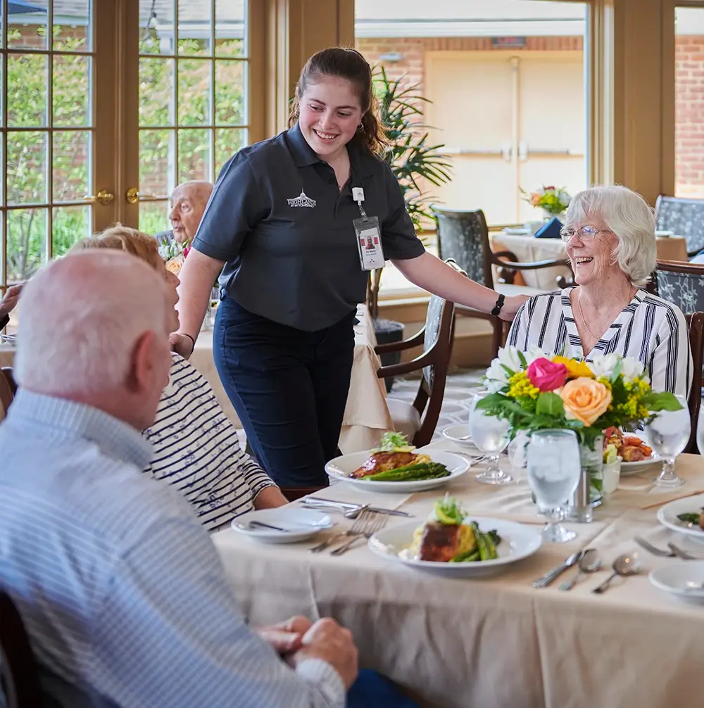 Server engaged in conversation with residents at table