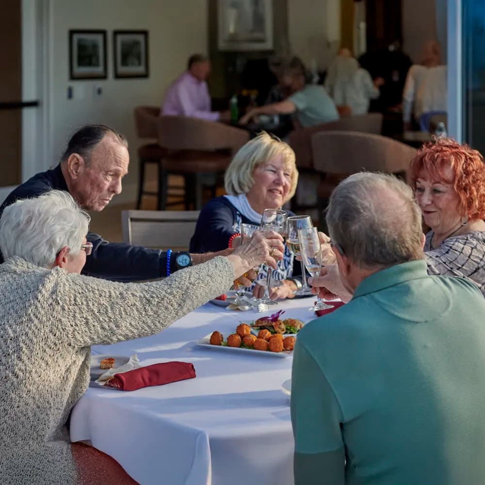 Residents toasting with drinks at a meal